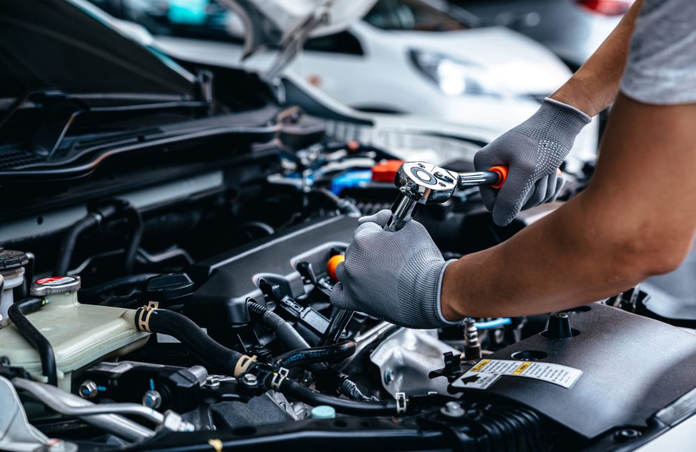 Mechanic using wrench while working on car engine at garage workshop, Car auto services and maintenance check concept.